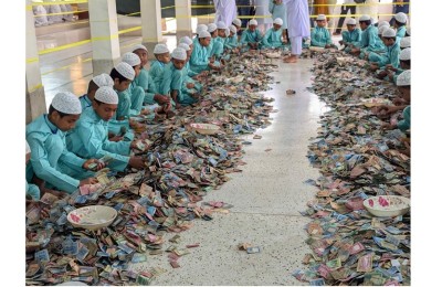 Men in uniform teal clothing sorting donations into different categories along the mosque floor.