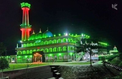 Nighttime view of the mosque glowing with bright green lights, highlighting its architecture.