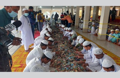 Volunteers sitting in rows carefully sorting piles of donated banknotes from the mosque donation boxes.
